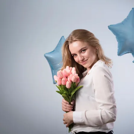 سيدة تحتفي باليوم العالمي للمرأة وتحمل الزهور والبالونات