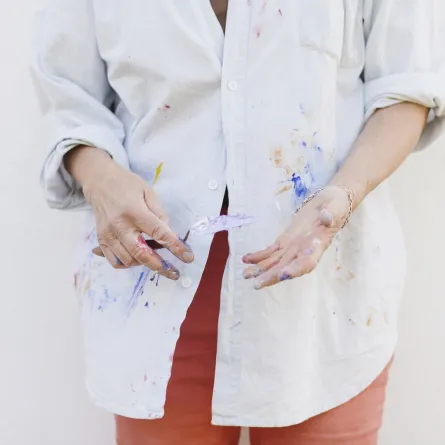 فنانة تحمل سكين الرسم، وترتدي قميصاً ملطخاً بالألوان