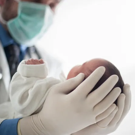 صورة لطبيب يحمل طفلًا رضيعًا