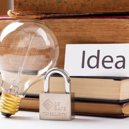 مصباح مضئ ومجموعة من الكتب وقفل رموز لحماية حقوق الملكية العالمي