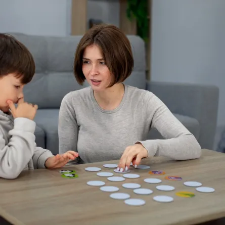 صورة لأم تجلس بجانب طفلها وتعلمه