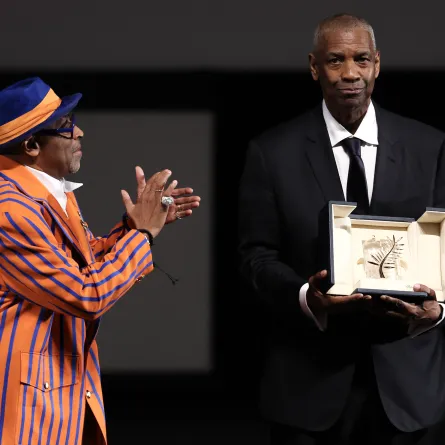 دينزل واشنطن يتسلم السعفة الذهبية الفخرية من المخرج سبايك لي في الدورة 78 من مهرجان كان السينمائي (Denzel Washington receives the Honorary Palme d'Or from director Spike Lee at the 78th edition of the Cannes Film Festival). مصدر الصورة:Sameer AL-DOUMY / POOL / AFP