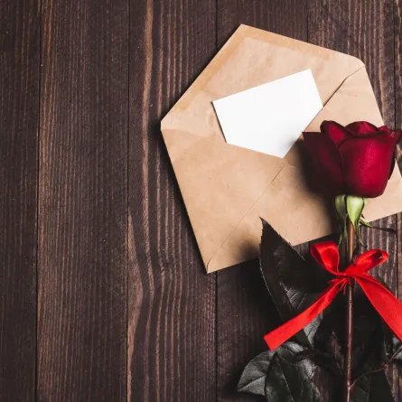 وردة حمراء موضوعة على ظرف به رسالة حب   