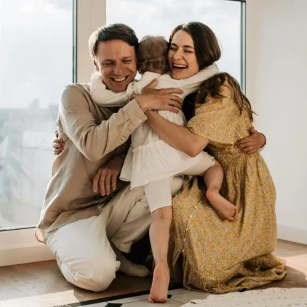 طفل يحتضن والديه وهما يحضنونه بمحبة 