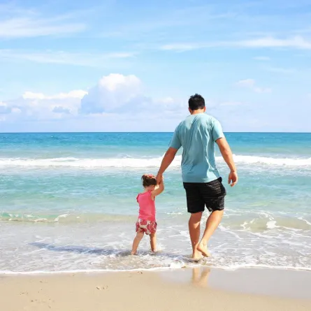 أب يتنزه مع صغيرته على شاطئ البحر 