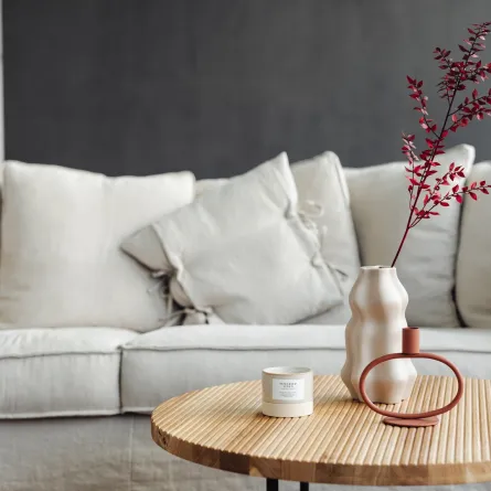 غرفة معيشة مع طاولة خشبية مزينة بمزهرية وشمعة