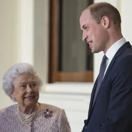 الملكة إليزابيث الثانية مع حفيدها الأمير ويليام بقصر باكنغهام في وسط لندن (Queen Elizabeth II with her grandson Prince William outside the Grand Entrance of Buckingham Palace in central London). مصدر الصورة: Victoria Jones / POOL / AFP