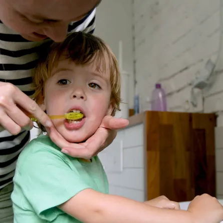 صورة أم تساعد طفلها على تنظيف أسنانه