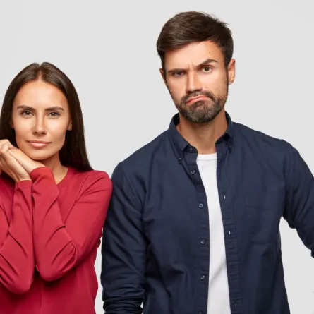 زوج يقف مقطبا حاجبيه والزوجة تضع يديها أسفل ذقنها   