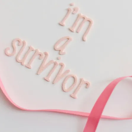  الشريط الوردي علامة سرطان الثدي ومعه عبارة أنا ناجية من سرطان الثدي
