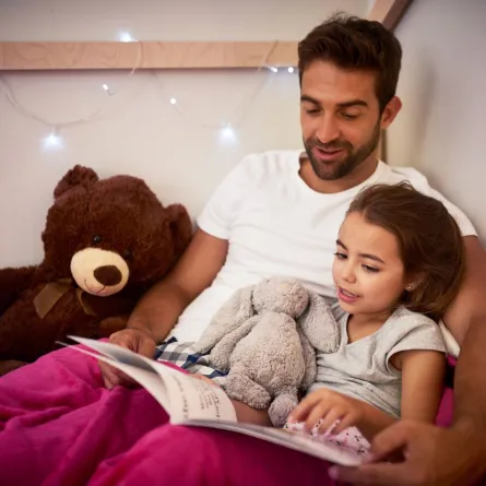 صورة أب يقرأ لطفلته