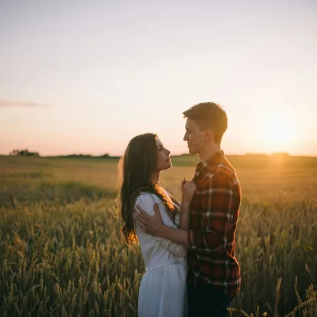 زوج يحتضن زوجته في يوم الحب يحيط بهما غروب الشمس
