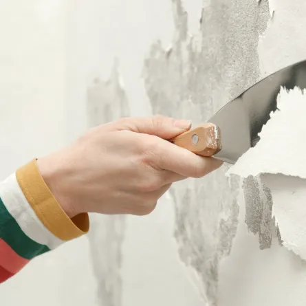 امرأة تزيل الطلاء المتقشر في المنزل