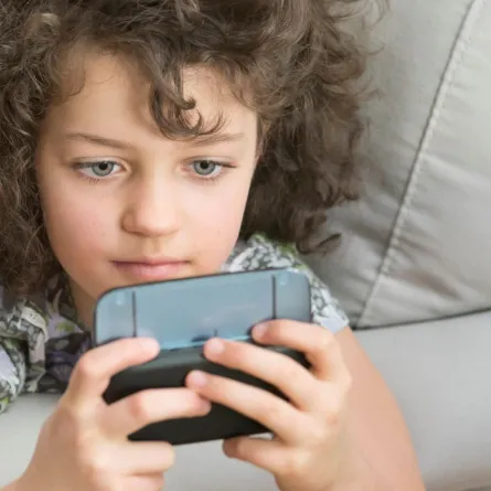 صورة طفلة تنظر إلى الموبايل