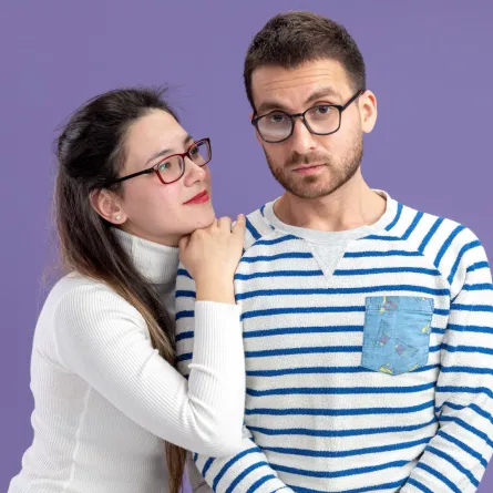 زوجة تضع ذقنها على كتف زوجها وتنظر لعينيه بذكاء  