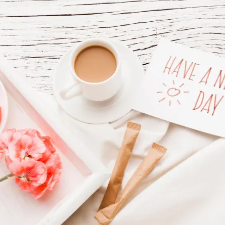 فنجان من القهوة حلوى وزهور وعبارة صباح الخير