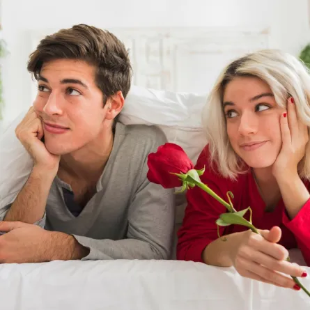 زوجة تهدي زوجها زهرة حمراء وتنظر له علامة على فهمه وهو يحاول أن يبدو متجاهلاً