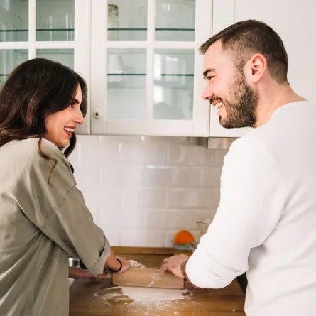 زوج يساعد زوجته ويتعاون معها بالأعمال المنزلية وهما يضحكان معاً