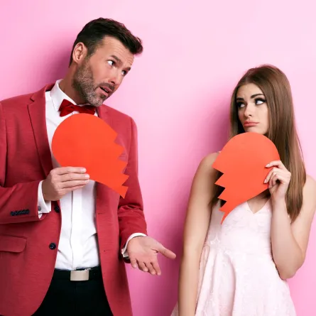 زوجة تمسك نصف قلب مكسور وزوج يمسك النصف الآخر علامة على انكسار العلاقة بسبب الندية 