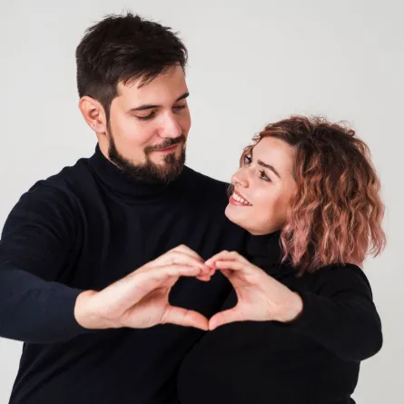 خطيبان يكونان معاً بيديهما شكل قلب ويبتسمان بسعادة   