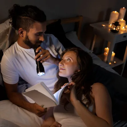 زوج يقرأ مع زوجته بعض الرسائل بالمساء على ضوء كاشف تجمعهما الرومانسية
