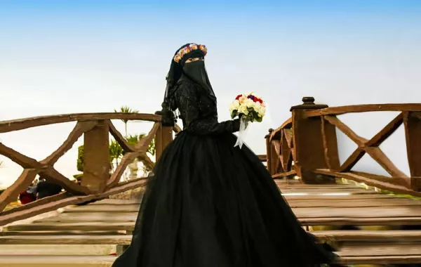 صور.. عروس تخرج عن المألوف بفستان زفاف أسود ونقاب 
