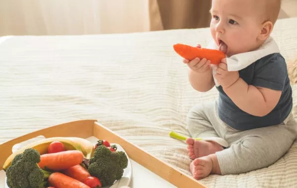 صورة لطفل تقدم له أمه الخضروات المشكلة المغذية المحتوية على عناصر غذائية مختلفة