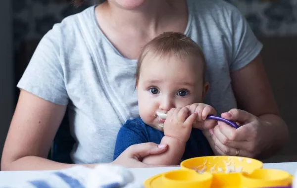 صورة لأم فرحة بقبول رضيعها للطعام الخارجي