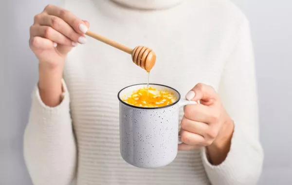 صورة لامرأة تمسك كوباً من العسل