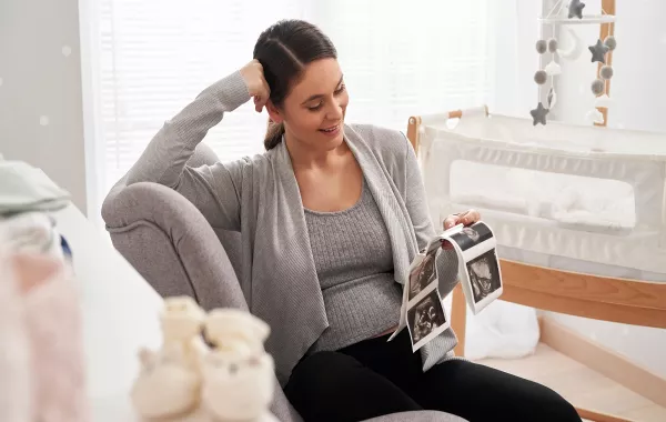 صورة لامرأة حامل تحمل صورة موجات فوق صوتية