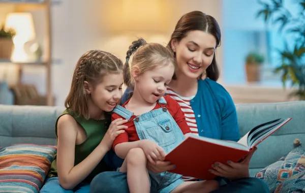 صورة لأم تقرأ قصة لطفلتيها