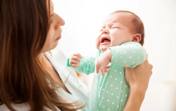 صورة لأم تحمل رضيعها الباكي