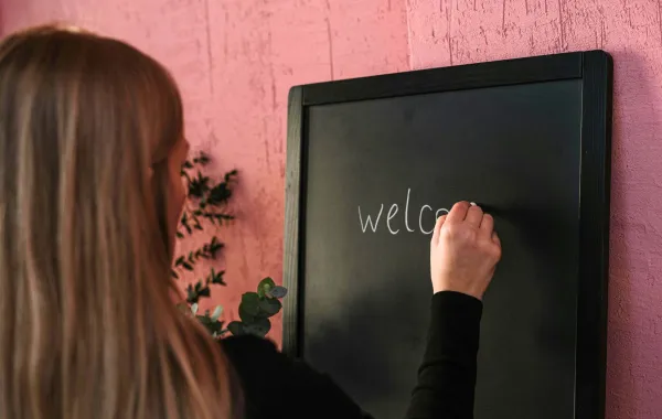 معلمة تكتب عبارة  ترحيبية بالطلبة   