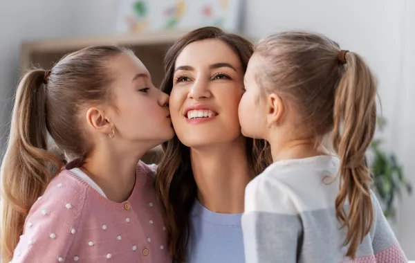 صورة لأم تتلقى قبلتين من بنتيها