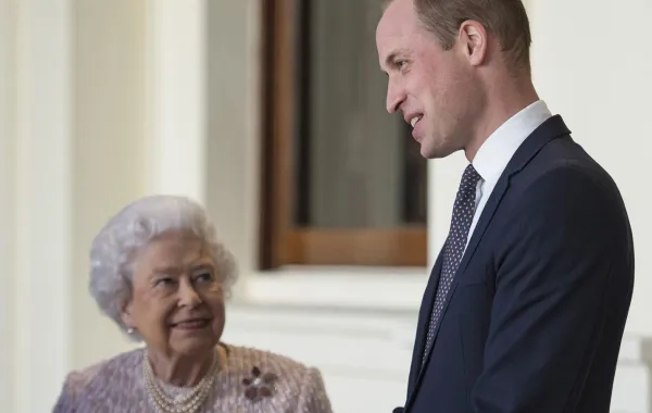 الملكة إليزابيث الثانية مع حفيدها الأمير ويليام بقصر باكنغهام في وسط لندن (Queen Elizabeth II with her grandson Prince William outside the Grand Entrance of Buckingham Palace in central London). مصدر الصورة: Victoria Jones / POOL / AFP
