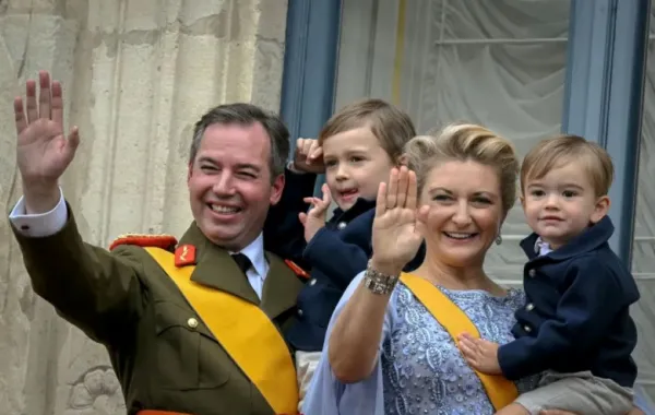 الدوق الأكبر غيوم والدوقة ستيفاني يحملان ابنيهما تشارلز وفرانسوا من شرفة القصر الدوقي الكبير (Grand Duke Guillaume and Duchess Stephanie hold their sons Charles and Francois from the balcony of the Grand Ducal Palace). مصدر الصورة: NICOLAS TUCAT / AFP