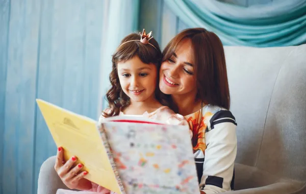 أم تقرأ لطفلتها  لتحفزها على السلوك الطيب صورة لأم تقرأ لطفلتها