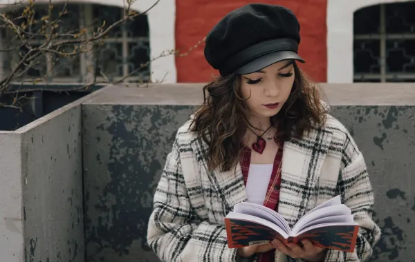 فتاة تقرأ كتاب في بلكونة المنزل