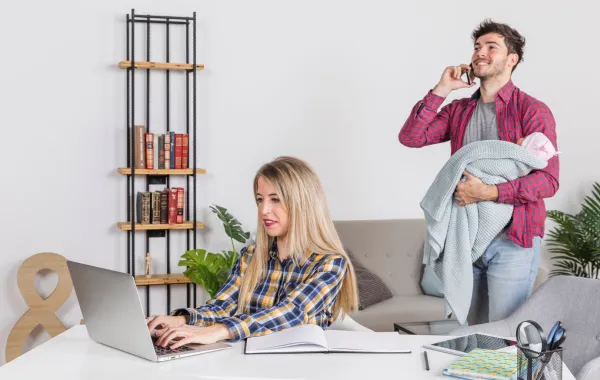 زوج يحمل ابنه في محاولة لمساعدة زوجته حتى تستكمل عملها عبر جهازها المحمول 