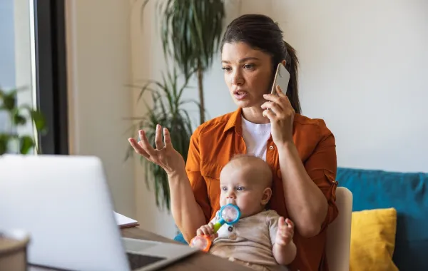أم عاملة تدير عملها وترعى طفلها معاً صورة لأم ترعى طفلها وهي تعمل