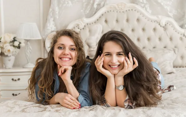 أختان تستلقيان على السرير وتضحكان بسعادة 