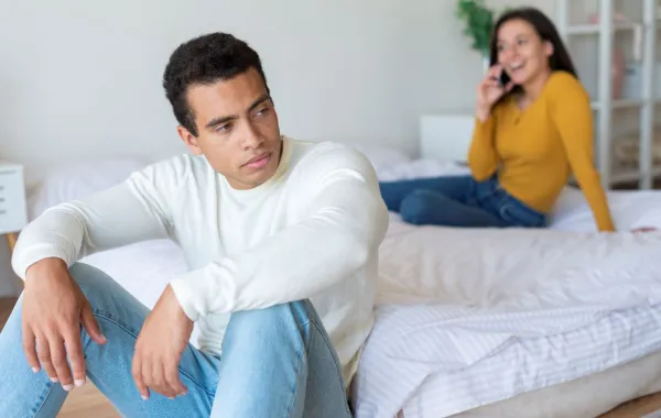 زوج يبدو غيورا غاضبًٍا من زوجته ومتضايق وهي تتحدث بالهاتف 