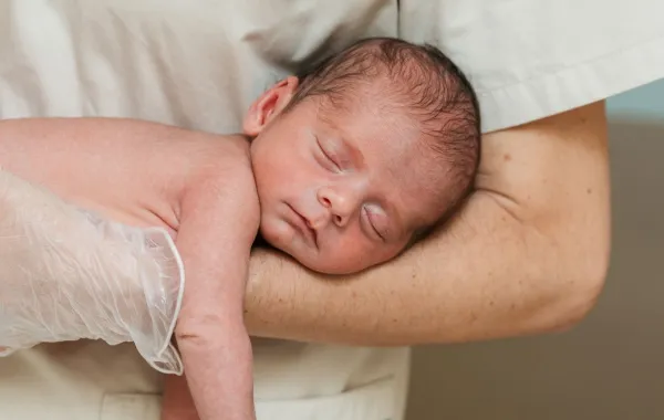 صورة ممرضة تحمل المولود