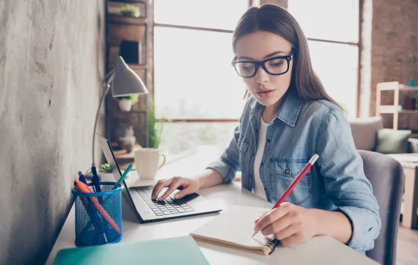 شابة يبدو عليها ملامح الجدية وهي تجتهد في عملها على جهازها المحمول