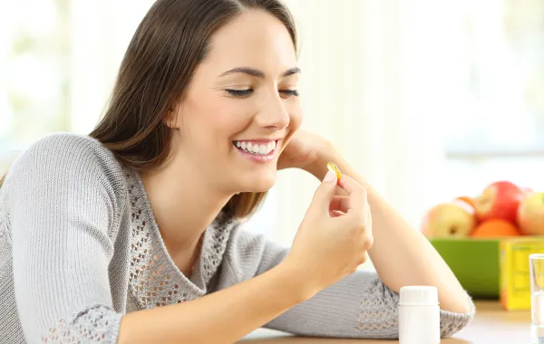 سيدة تتناول المكملات الغذائية لتوفير العناصر الغذائية