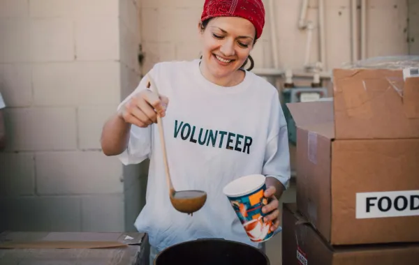 إحدى المتطوعات تصب الحساء في أكواب للمحتاجين