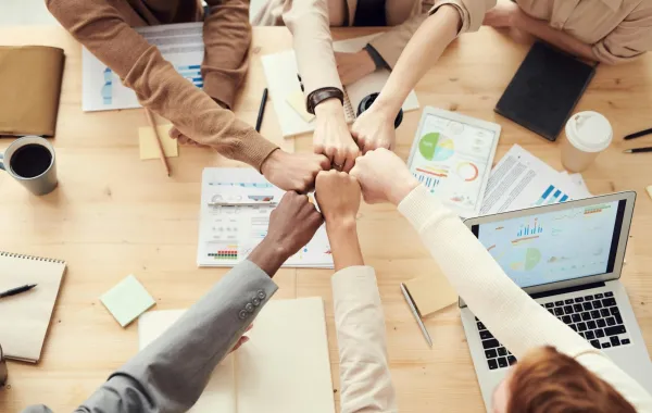 مجموعة من الشباب يضمون أيديهم معًا حيث يتعاونون على قضاء عملهم