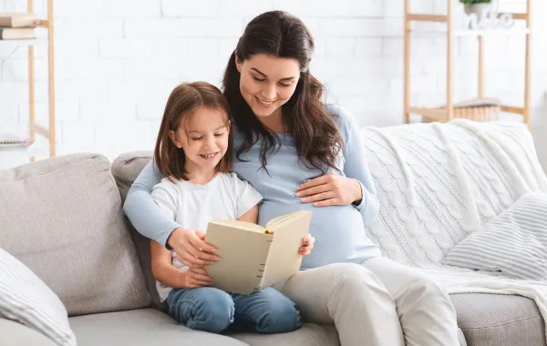 الأم تقرأ والابنة والجنين يستمعان
