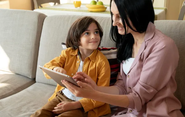 صورة لأم تعلم طفلها على جهاز لوحي