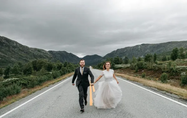 زوج يمسك بيد زوجته في زفافهما ويجري معها بسعادة